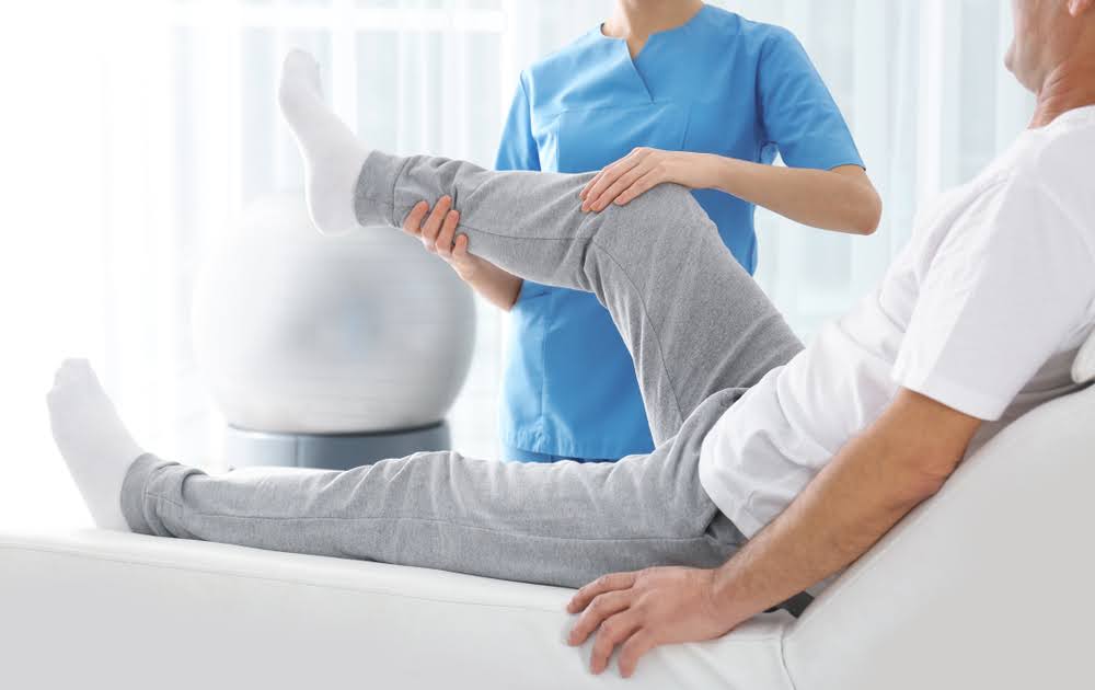 Physiotherapist working with patient’s knee